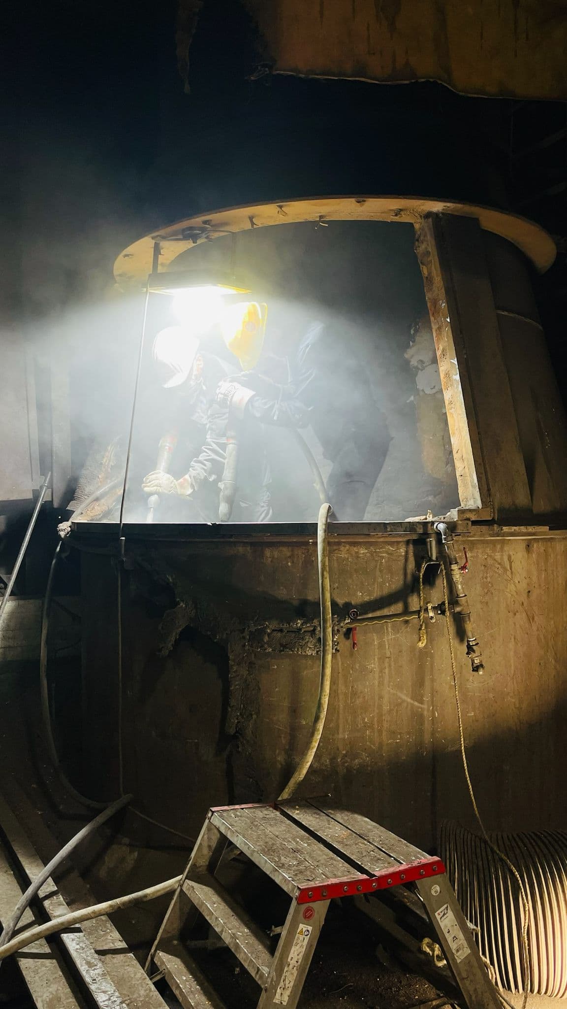 Arbeiter bei Abbrucharbeiten in einem Industrieofen